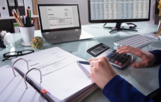 Hands in Front of Calculator, Notebooks and Computer