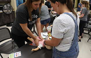 Two Students Performing CPR On A Baby Manikan