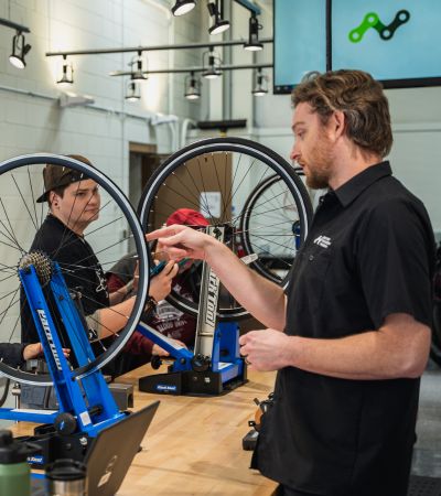 Man Pointing at a Bicycle Tire in a Classroom