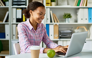 smiling woman works on a laptop in a library