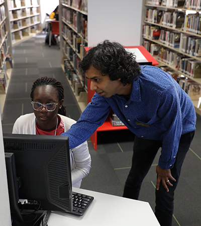 Male Student Pointing at Computer Screen in Front of Female Student