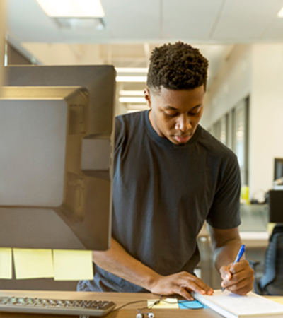 Man in Front of Computer and Writing on Paper